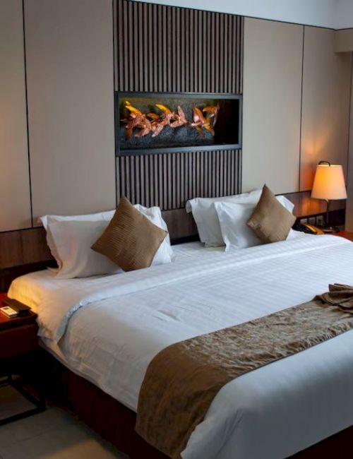 A stylish hotel room with a large bed, two bedside lamps, cushioned headboard, wall art above the bed, and a window with curtains on the side.
