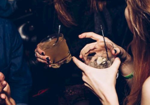 People are socializing and holding drinks at what appears to be a lively gathering or party.