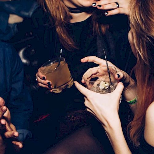 People are socializing and holding drinks at what appears to be a lively gathering or party.