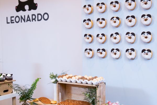 A decorated table with various pastries and a wall displaying panda-themed donuts. The wall has 