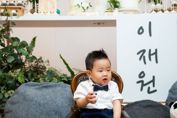 A child sits in a chair with a panda-themed backdrop. Korean text and the name 