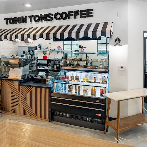 The image shows a modern coffee shop with a black-and-white striped awning, labeled 