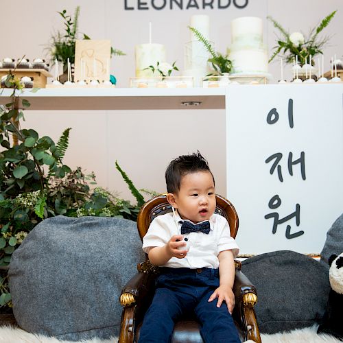 A child in a white shirt and blue bow tie sits on a chair, with 