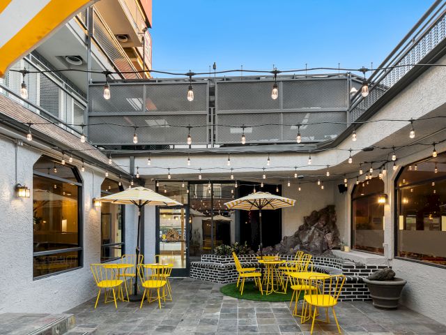 A cozy outdoor seating area with yellow chairs, umbrellas, and string lights