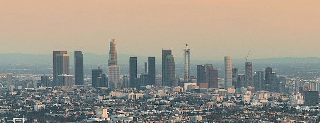 A cityscape of a major urban area with numerous high-rise buildings during sunset, featuring a mix of modern and older architecture.