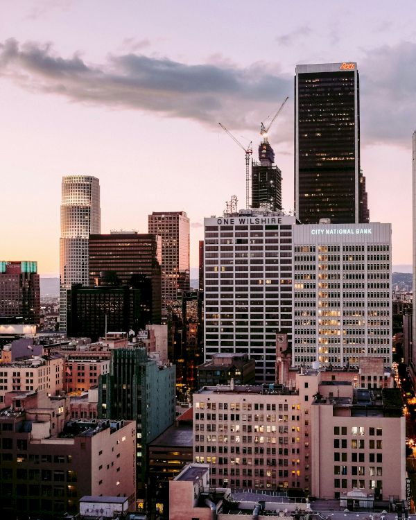 City skyline at dusk with buildings illuminated by the setting sun.