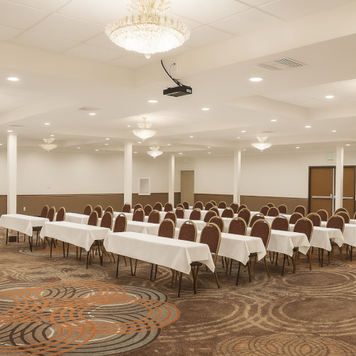 A conference room with tables, chairs, chandeliers, and a patterned carpet, ready for an event or meeting.