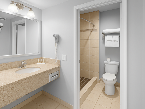 A modern bathroom with a sink, mirror, hairdryer, toilet, shower, and neatly arranged towels on a rack.