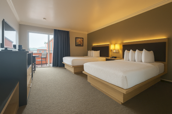 A hotel room with two large beds, a TV, a balcony with chairs, and a warm-lit decor completes the cozy ambiance.