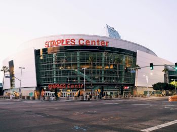 The image shows the exterior of Staples Center, a large sports and entertainment venue in an urban setting.