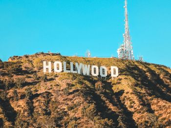 A view of the Hollywood sign on a hill with antennas under a clear blue sky.