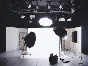 A photography studio setup with lights, umbrellas, and a backdrop ready for a shoot.