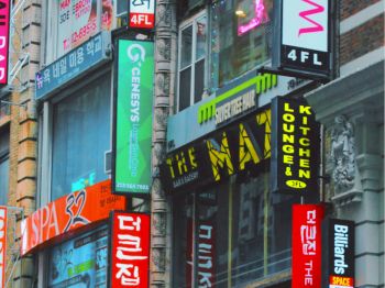 The image shows a busy street with various colorful signs for restaurants, salons, and other businesses.